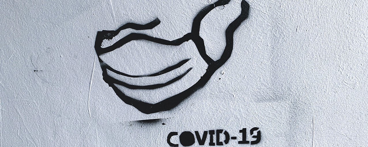 A imagem mostra o desenho de uma máscara facial, embaixo dela está escrito COVID-19